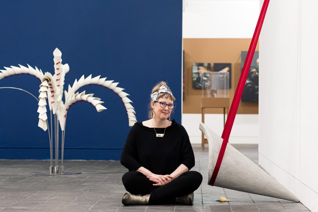 Anna Berry sat on the floor next to her concrete and ceramic sculptures