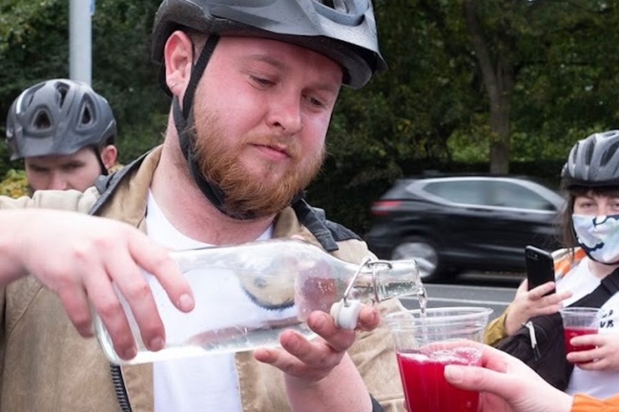 Photo of Phillip wearing a bike helmet and pouring liquid into a cup