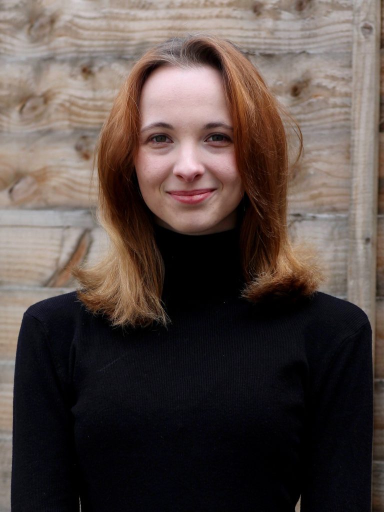 A photo of Kasia looking at the camera. She is wearing a black top and has auburn coloured hair.